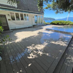A large, stepped patio deck custom built to a beautiful white home with a large bay window